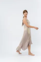 Vestido midi color lila metálico de breteles finos regulables, escote en V y ruedo asimétrico con leve vuelo.