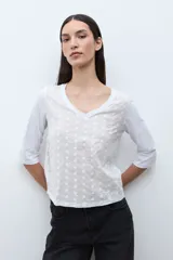 Remera de manga tres cuartos con escote en V, confeccionada en tela con textura de broderie en el frente.