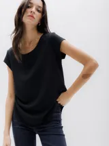 Top de manga corta color negro, con cuello redondo y cierre metálico visible en la parte posterior. Presenta un diseño de corte recto con ruedo ligeramente redondeado y más largo en la parte trasera.