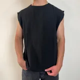 Musculosa de tejido de punto en color negro, con corte oversize y terminaciones desflecadas en las sisas.