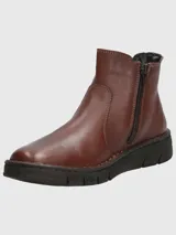 Bota tipo Chelsea de cuero color marrón, con paneles elásticos laterales en color negro y suela de goma dentada.