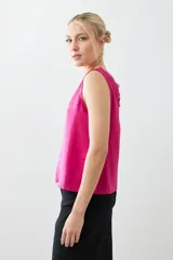 Top satinado color fucsia con escote en V y detalles de encaje en el borde del escote. Sin mangas y de corte holgado.