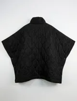 Poncho acolchado color vino tinto, con cuello alto y cierre frontal parcial. Presenta un patrón de costuras capitoné en forma de hoja o diamante y bolsillos delanteros.