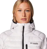 Campera técnica Columbia Titanium, modelo Arctic Crest, de diseño acolchado con tecnología Omni-Heat Arctic. Cuenta con capucha integrada, cierre frontal completo, bolsillo en el pecho y bolsillos laterales con cremallera, todos en color negro contrastante sobre la base blanca.
