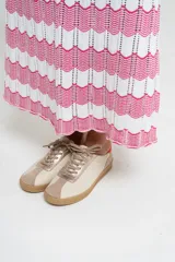 Zapatillas deportivas de cuero color beige con detalles en naranja y suela marrón.