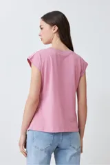 Blusa de algodón color rosa pastel con frente de tela broderie, cuello redondo y mangas cortas con terminación al corte.