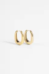 Aros de acero quirúrgico hipoalergénico, diseño ovalado y chunky con acabado dorado brillante.