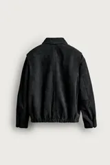 Cazadora de piel con acabado serraje de corte relaxed fit, color negro, con cuello solapa, bolsillos de vivo en la cadera, bajo elástico y cierre frontal con cremallera de doble dirección. Colección especial Aaron Levine x ZARA.