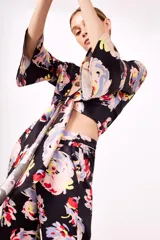 Camisa negra con estampado floral multicolor, escote en V cruzado y mangas acampanadas.