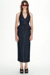 Falda midi de tiro alto confeccionada en denim oscuro, con cinco bolsillos estilo jean, cierre frontal con cremallera y botón, y abertura en la espalda. Presenta pespuntes en color rojo contrastante.