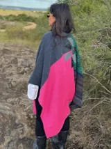 Ruana abierta de tejido de punto con diseño de bloques de color y bolsillos frontales aplicados. Presenta una textura variada y un corte holgado, ideal para superponer sobre otras prendas.