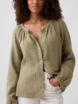 Camisa de muselina color verde militar, de manga larga abullonada, con cuello redondo fruncido y cierre frontal de botones.