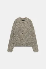 Chaqueta de punto de cuello redondo y manga larga, con textura jaspeada en tonos tierra y azul. Presenta cierre frontal con botones oscuros y dos bolsillos de plastrón en el delantero.