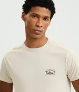 Remera de hombre con tecnología dry, cuello redondo y mangas cortas. Presenta un diseño minimalista con estampado lettering 1921 en el pecho y detalle de textura en los hombros.