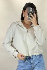 Buzo deportivo color blanco con cuello polo y cierre frontal parcial. Presenta mangas largas con puños elásticos y ruedo ajustable con cordón elástico.