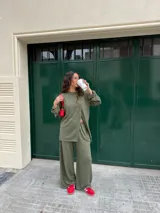 Conjunto gris melange confeccionado en lanilla, compuesto por una remera de manga larga con diseño cruzado en el frente y un pantalón largo de corte ancho con bolsillos.