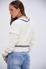 Sweater de punto trenzado color blanco, con cuello en V y detalles de rayas negras en el cuello, puños y ruedo. De corte corto y manga larga.