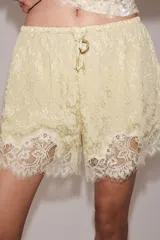 Shorts de tiro medio confeccionados en tejido jacquard con mezcla de cupro, en color beige. Presentan cintura elástica ajustable con cordones y detalle de aplicación de encaje a tono en el ruedo.