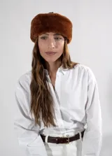 Gorro tipo ushanka o de piel sintética en tono óxido, con diseño reversible y textura suave de peluche.