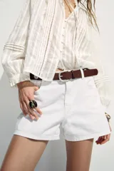 Shorts de jean color marrón oscuro, de tiro medio y corte mom fit. Con cinco bolsillos, cierre frontal con cremallera y botón.