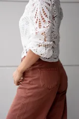 Pantalón de jean color ladrillo, de corte recto y tiro alto, con aberturas laterales en el ruedo y detalle de botones.