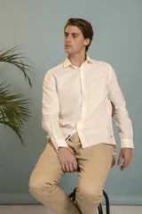 Camisa de manga larga en color salmón con estampado de pequeños motivos geométricos oscuros, cuello clásico y cierre frontal con botones.