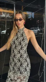 Vestido midi de encaje floral color beige sobre base negra, con cuello halter y falda con vuelo.