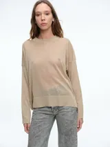 Sweater de tejido fino con hilo brillante y acabado levemente transparente. Presenta cuello redondo, hombros caídos y mangas largas amplias con un corte relajado y fluido.