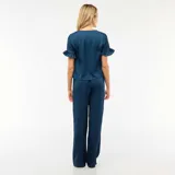 Conjunto de pijama compuesto por una blusa de manga corta con volados y cierre frontal mediante lazos, y un pantalón de corte recto con cintura elástica, confeccionado en tela con textura tipo crepé.