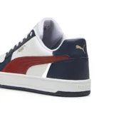 Championes Puma Caven 2.0, color blanco con detalles en azul marino y franja lateral roja. Presenta cordones blancos, perforaciones en la puntera y suela de goma blanca con base azul.