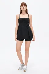 Vestido corto negro de poliamida, con tirantes finos regulables tipo lencero, escote recto y diseño ajustado con falda evasé con tajo lateral.