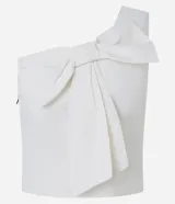 Blusa blanca de un solo hombro confeccionada en crepé, con un llamativo lazo decorativo en el frente. Modelo de la marca A Collection.