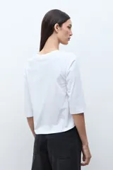 Remera de manga tres cuartos con escote en V, confeccionada en tela con textura de broderie en el frente.