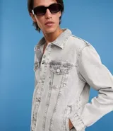 Campera de jean de hombre, color celeste claro con efecto desteñido y desgastado. Presenta cuello, manga larga, cierre frontal con botones blancos y dos bolsillos con solapa y botón en el pecho.