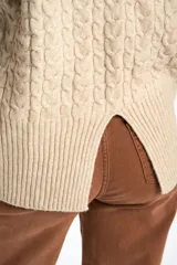 Sweater de punto color beige melange, con cuello redondo y tejido trenzado en el cuerpo y mangas. Presenta un borde inferior de punto acanalado.