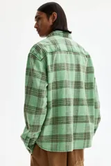 Camisa H&M de sarga de algodón verde con diseño de cuadros oscuros, cuello inglés, un bolsillo en el pecho y cierre frontal de botones.