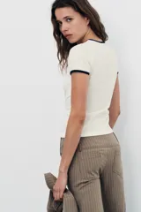 Pantalón capri de tiro medio con raya diplomática en tonos beige y marrón. Presenta trabillas, bolsillos laterales y cierre frontal con cremallera y botón metálico.