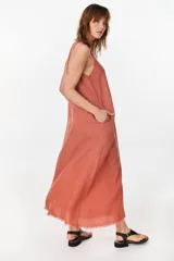 Vestido midi verde de lino italiano, con diseño sin mangas, cuello redondo y estampado de líneas onduladas punteadas. Cuenta con bolsillos laterales.