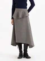 Pollera midi de corte irregular con estampado Príncipe de Gales. Presenta un diseño de falda plato con un volado caracol superpuesto en la cintura y ruedo asimétrico.