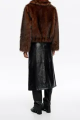 Chaqueta corta de corte globo confeccionada en pelo sintético color marrón, con cierre frontal de cremallera metálica y cuello camisero amplio. Presenta manga larga recta y bolsillos laterales de vivo.