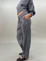 Pantalón de vestir gris con bolsillos laterales, pretina a la cintura y tablas en los bajos.