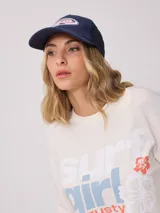 Gorra azul marino de lona con visera curva y malla trasera. Presenta logo bordado en el frente.