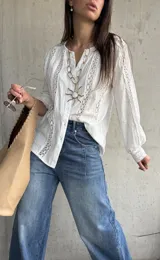 Camisa blanca de manga larga con detalles de encaje y diseño abotonado en la parte delantera.