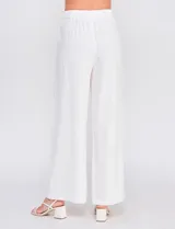 Pantalón palazzo color blanco, confeccionado en mezcla de lino y viscosa, de tiro alto con cierre frontal de botones, pinzas en la cintura y piernas anchas.