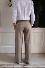Pantalón de corte sastrero con pierna recta, confeccionado en gabardina y tencel. Presenta un diseño en color beige con detalle de rayas laterales en contraste.