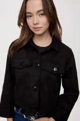 Campera negra de efecto gamuzado con cuello camisero, cierre frontal de botones, bolsillos plaqué en el pecho y detalles de costuras decorativas y calados.