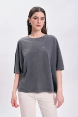 Remera manga corta de color gris oscuro con efecto lavado, corte oversize y cuello redondo. Cuenta con pequeños apliques brillantes distribuidos por toda la prenda.