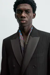 Blazer de corte regular confeccionada en tejido con lana, con diseño de doble botonadura. Presenta solapas de muesca en tejido combinado a tono, manga larga con puños abotonados, bolsillos laterales con solapa y bolsillo de vivo en el pecho.