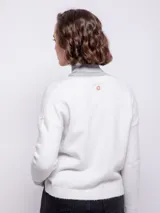 Cardigan corto de tejido tramado, con escote en V, cierre frontal con botones a tono y mangas largas con puños ajustados.