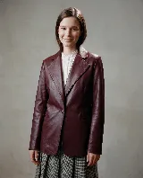 Blazer de cuero bovino color bordó, con silueta entallada, solapas clásicas y cierre frontal con un botón. Presenta mangas largas con detalles fruncidos que aportan textura.